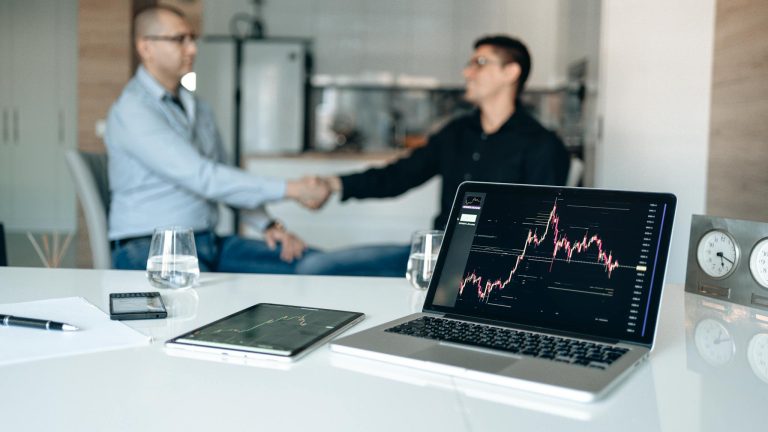 Two businessmen shake hands at a desk